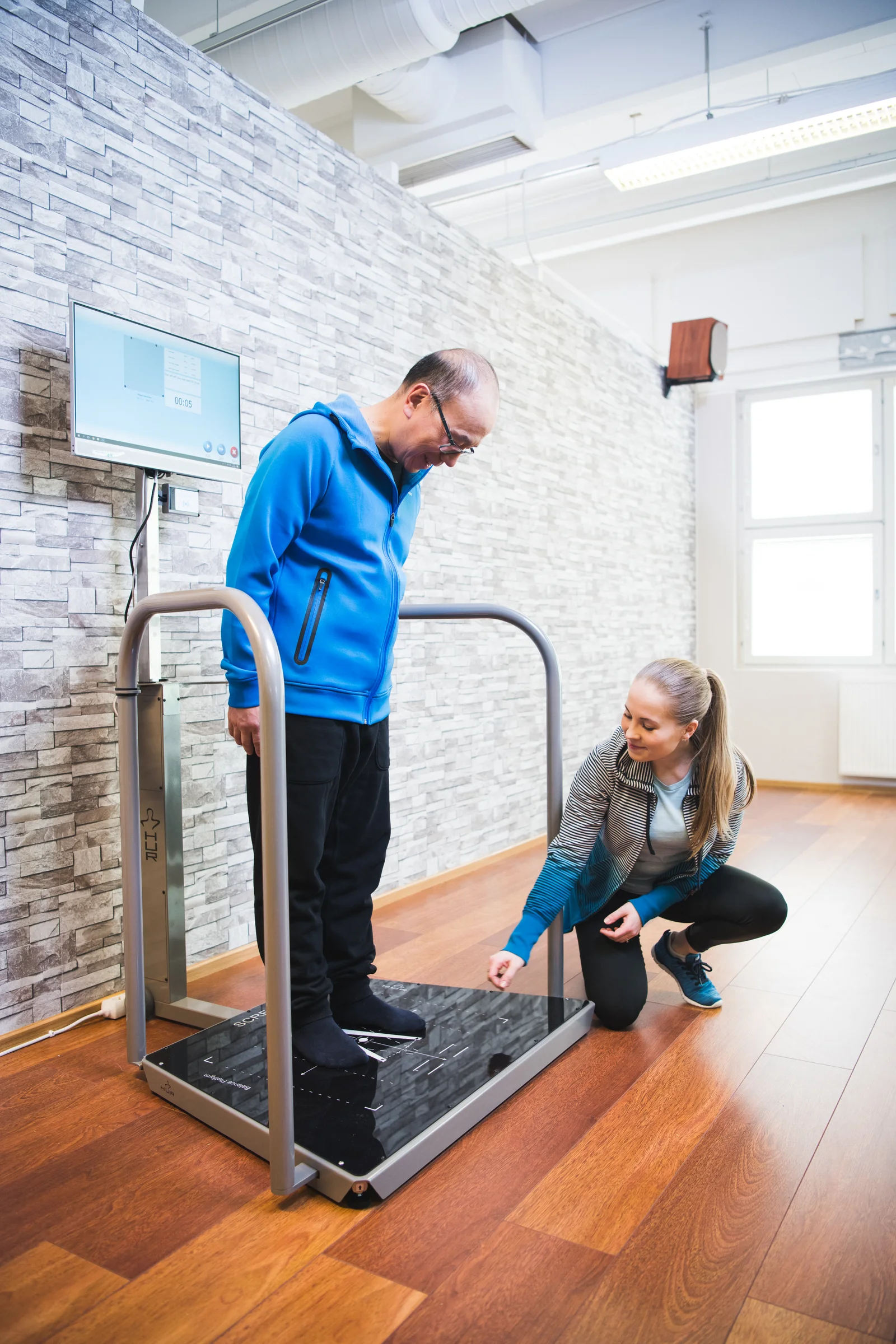A staff member supporting an exerciser on a balance assessment platform